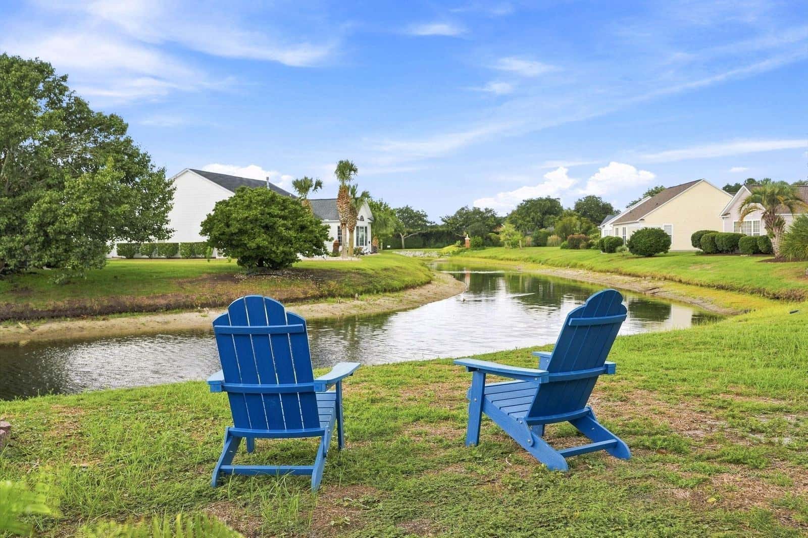 Two chairs set out on the grass facing calm water at Barefoot Resort, North Myrtle Beach