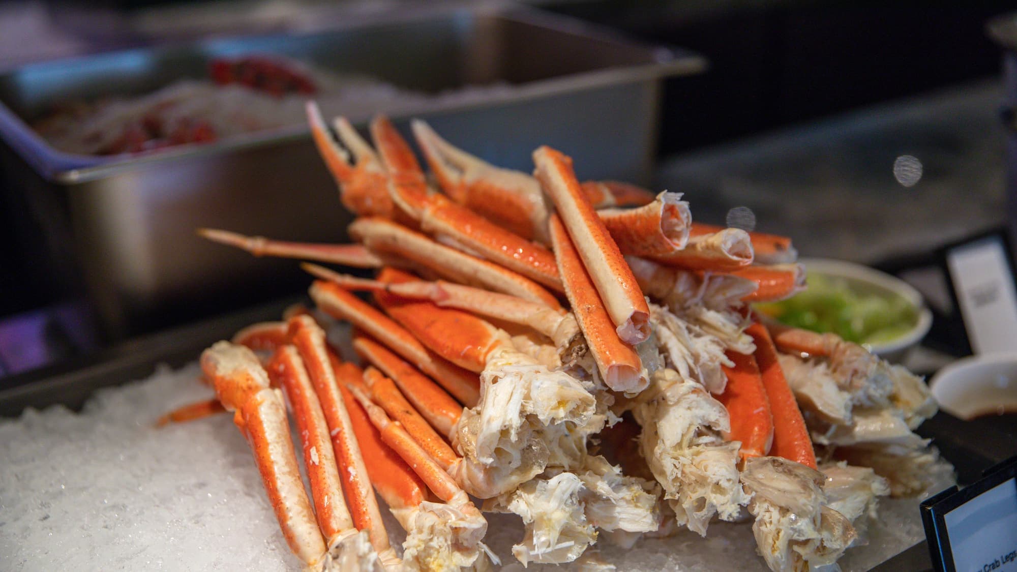 Snow crab legs piled high on a steel buffet tray over ice