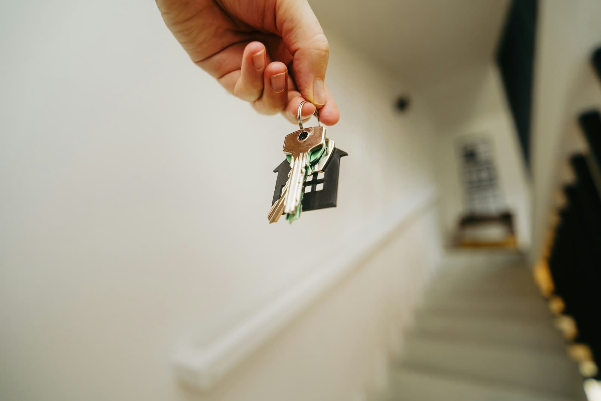 A hand holding a set of house keys on a stairway