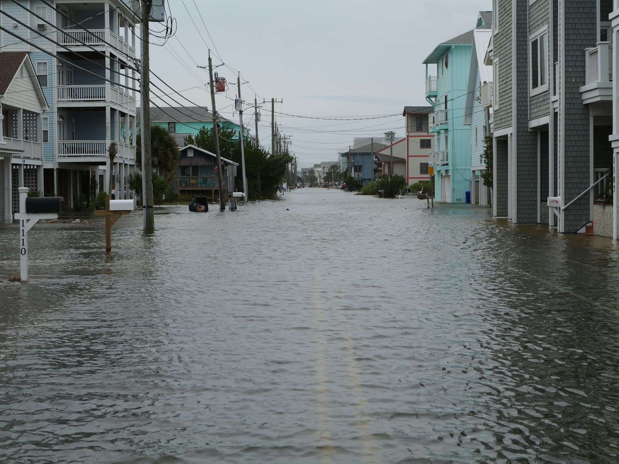Floodwater covering a street lined with raised beach houses