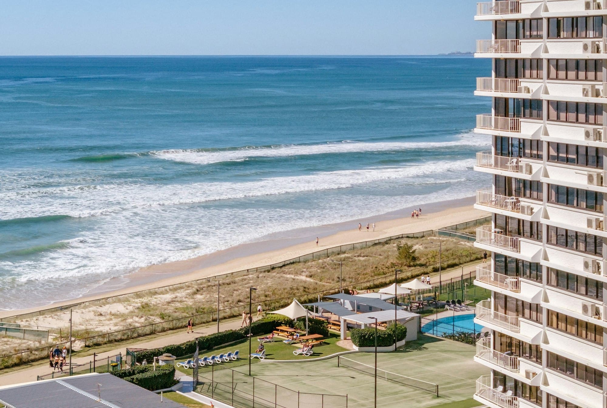 A beachfront high-rise with pool and tennis courts overlooking the ocean