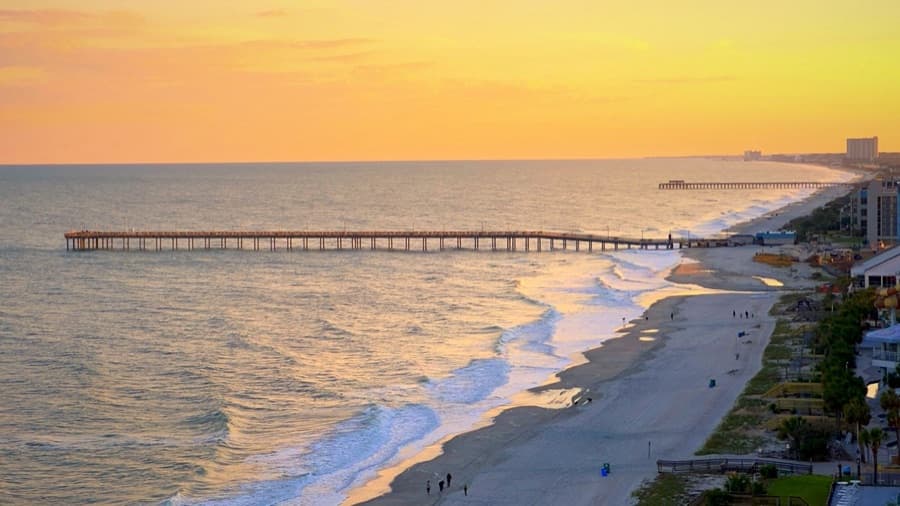 The Myrtle Beach shoreline at sunset, with a fishing pier and high-rises along the strand