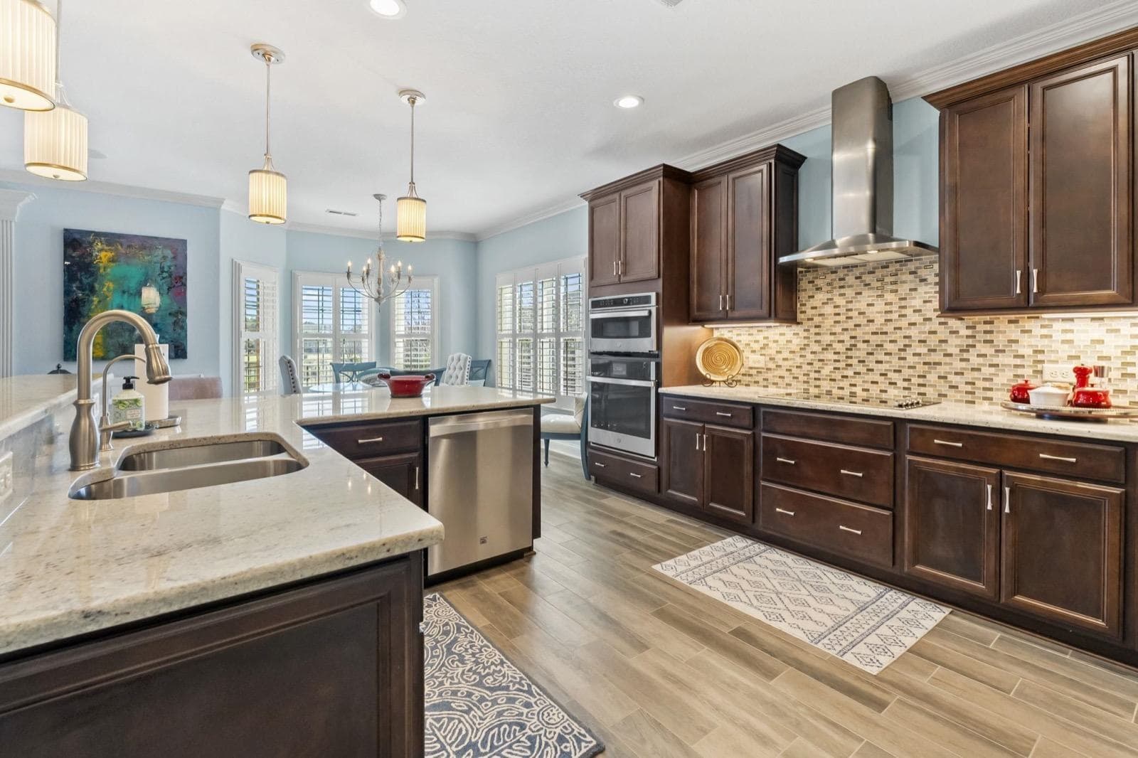 A kitchen with dark cabinets, a granite island and pendant lights, one of Robin's listings
