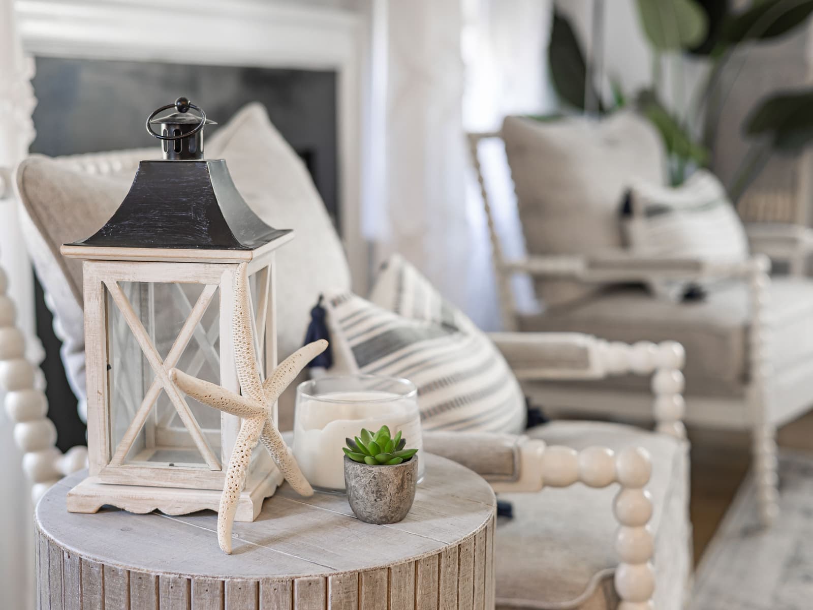 A whitewashed lantern, starfish and candle styled on a round wooden table