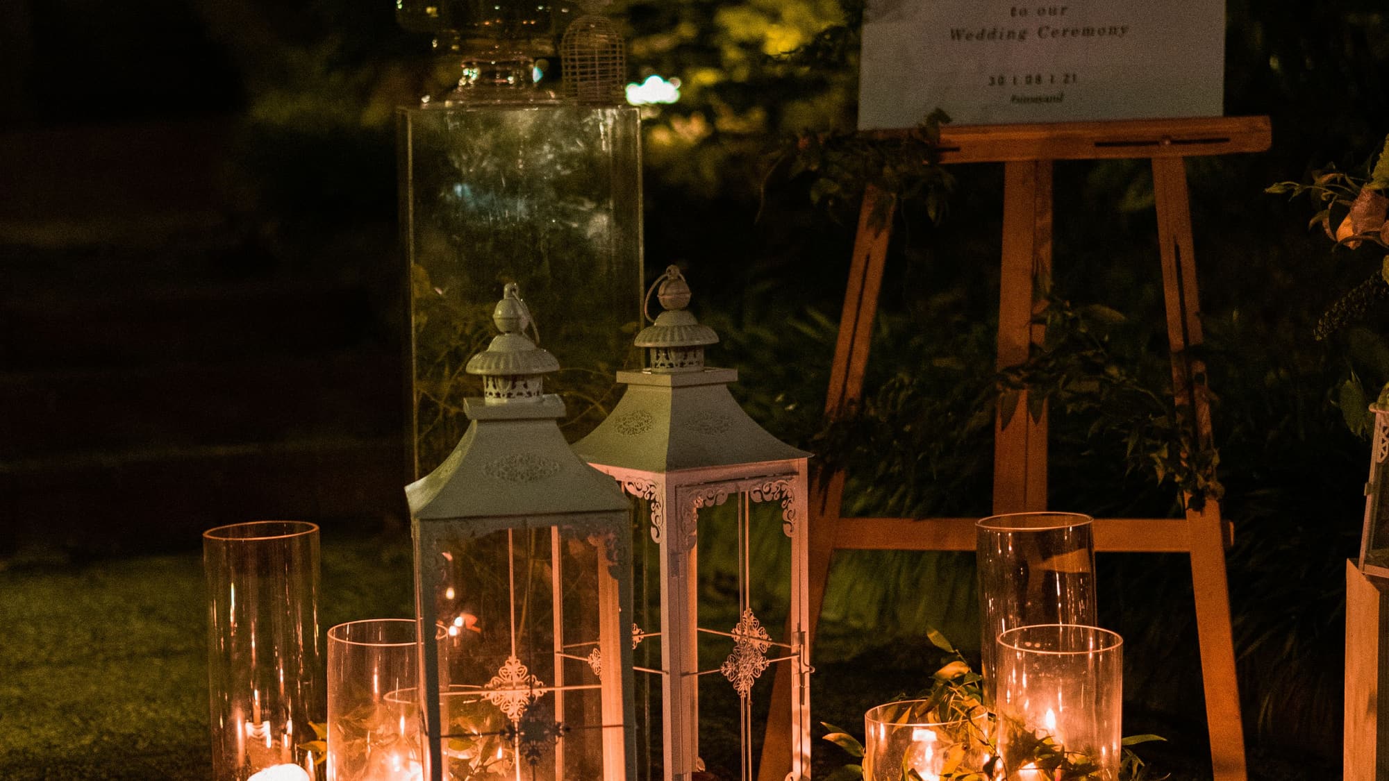 A path at night lined with glowing candle lanterns set in the grass