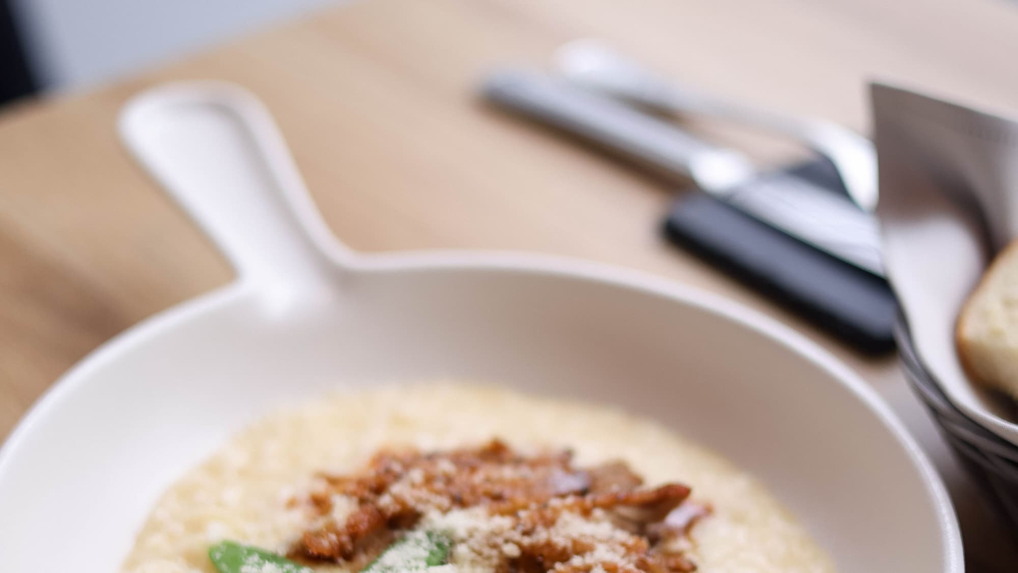 A creamy pan of grits topped with a savory sauce, with a spoon resting in it