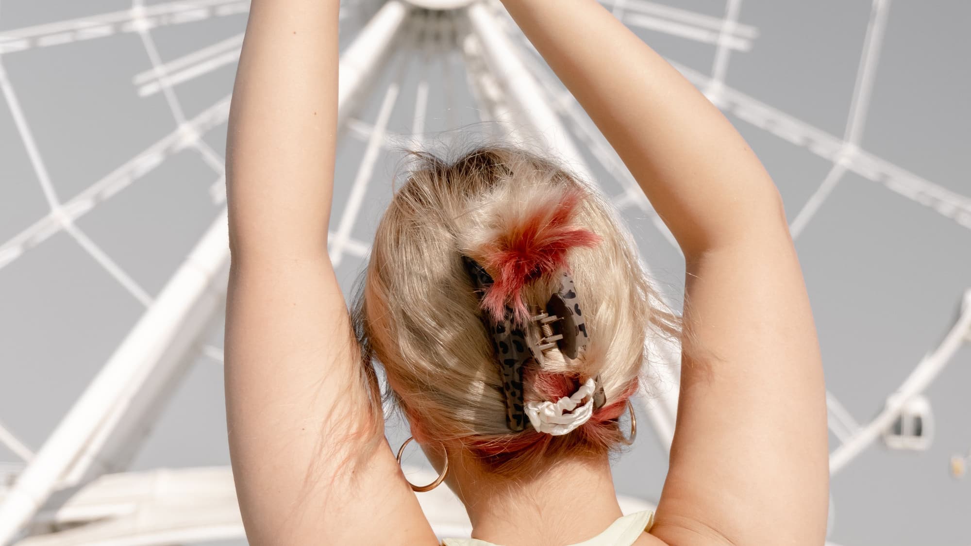 A woman seen from behind with her arms raised, her hair twisted up and held in a claw clip