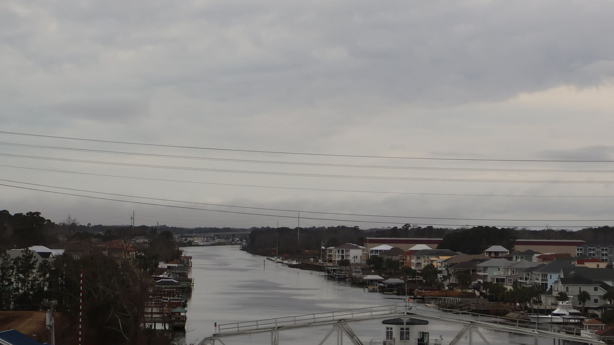 The Intracoastal Waterway at North Myrtle Beach on an overcast day, with docks and waterfront houses along the right bank and a swing bridge in the foreground