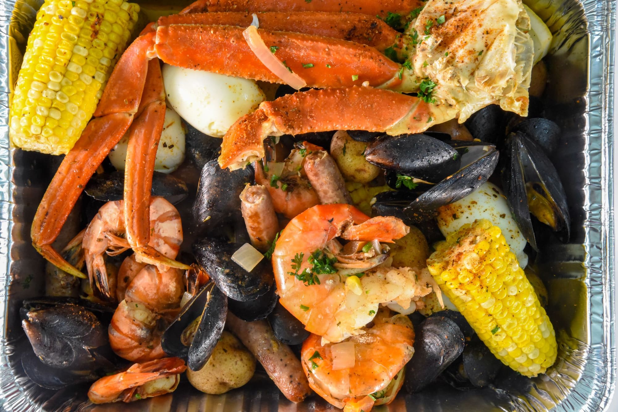 A spread of shrimp, crab legs, mussels and corn on the cob piled into a tray