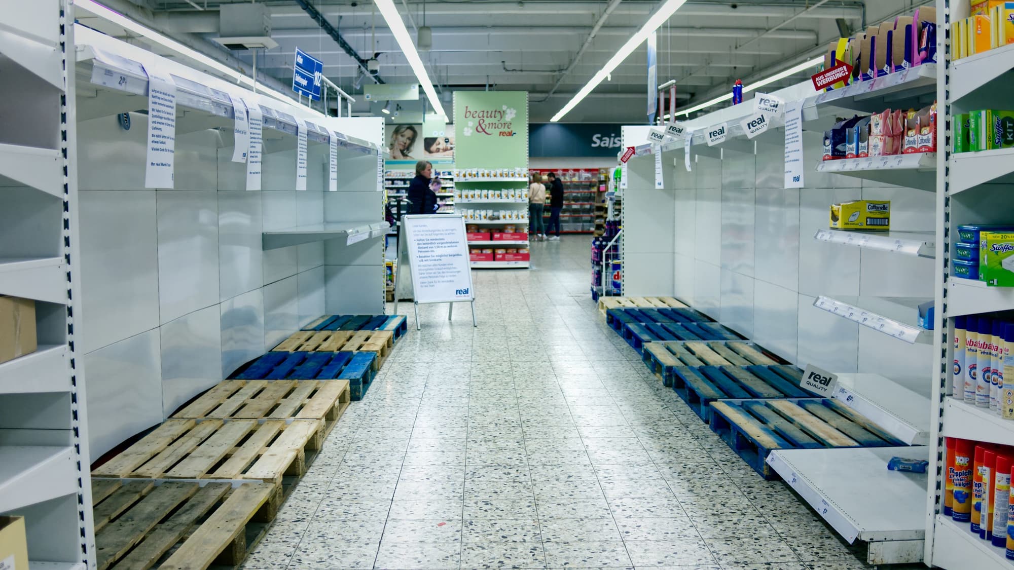 A grocery store aisle with long rows of completely empty shelves