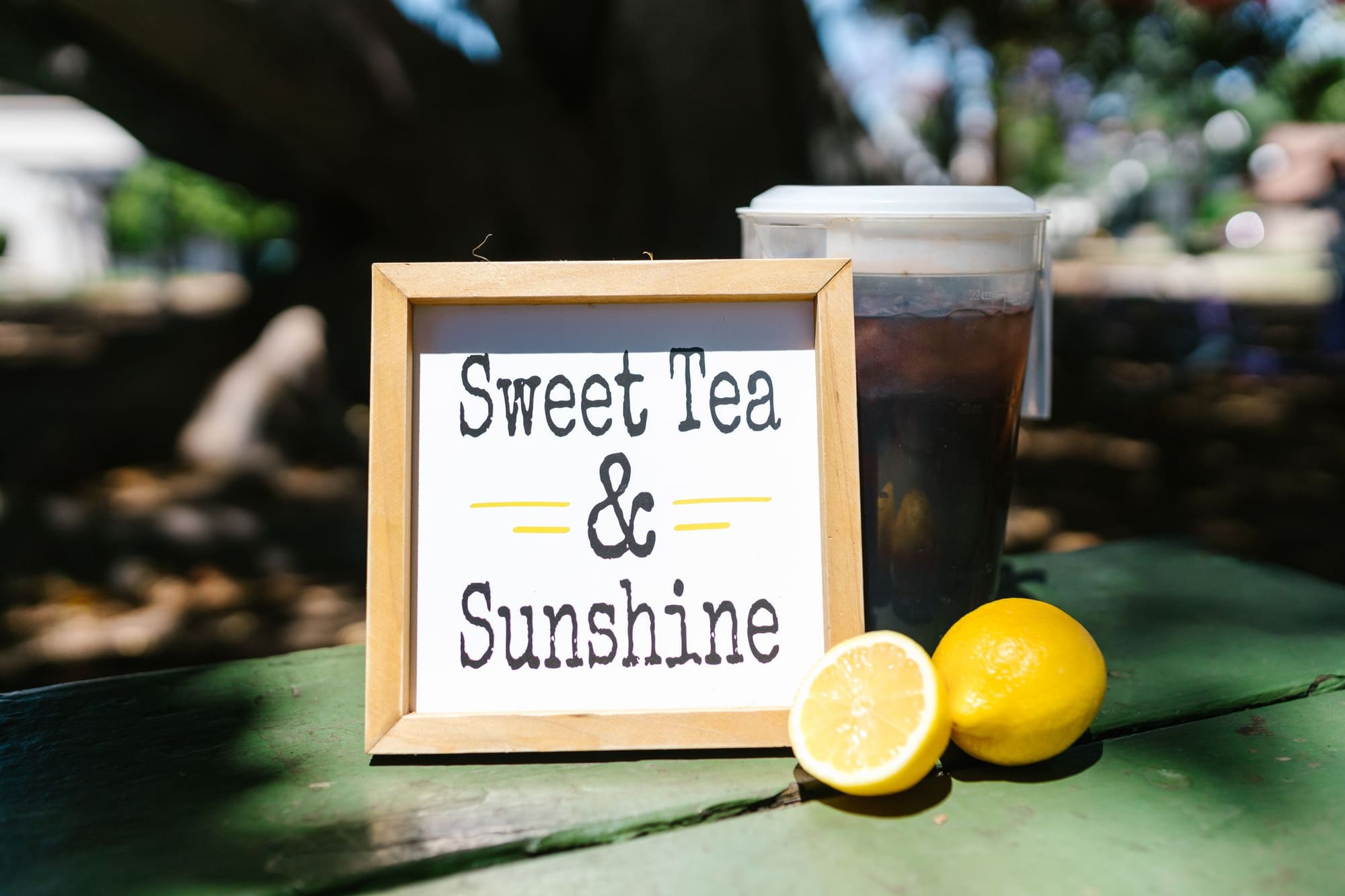 A hand-lettered sign reading Sweet Tea and Sunshine propped beside a glass of iced tea and a halved lemon