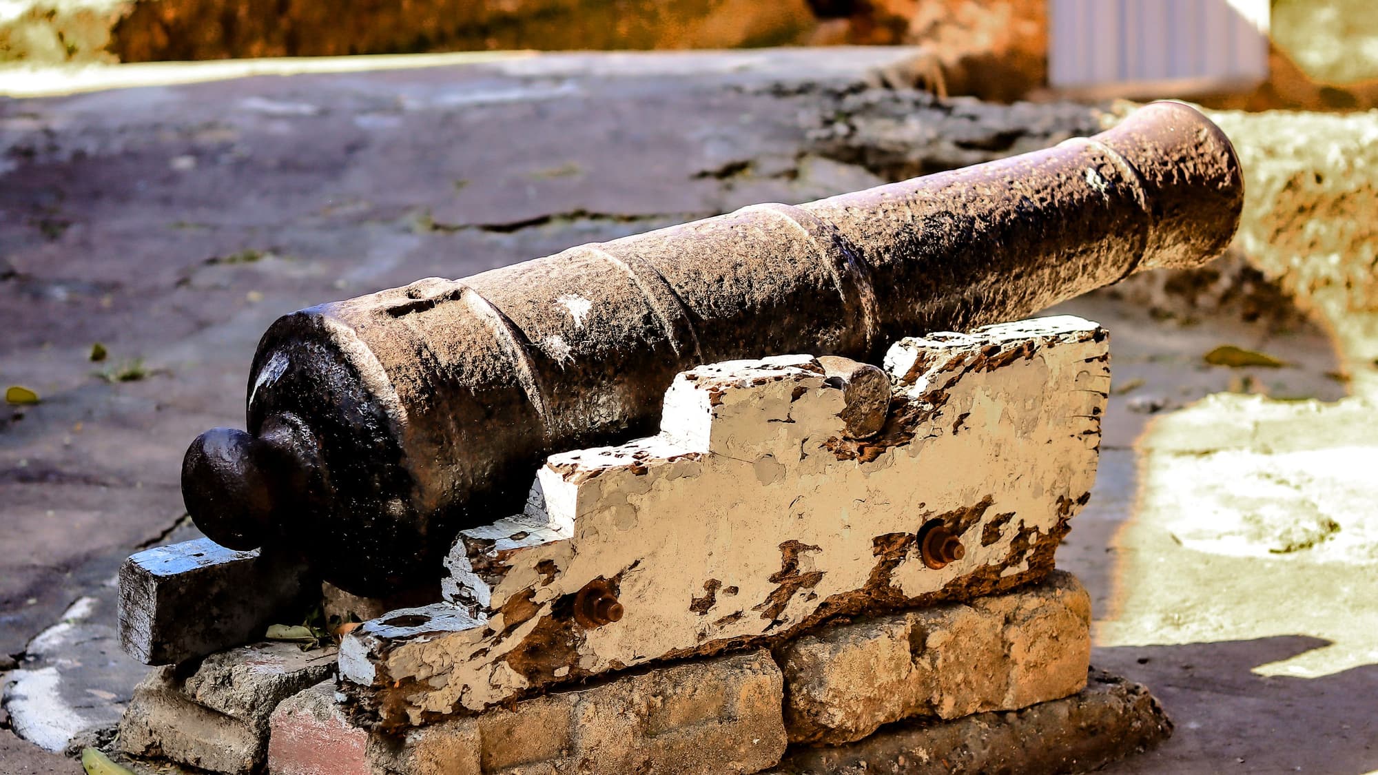An old iron cannon resting on a weathered stone wall